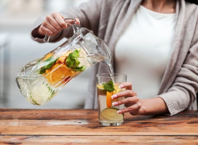 woman pouring water infused with fruit