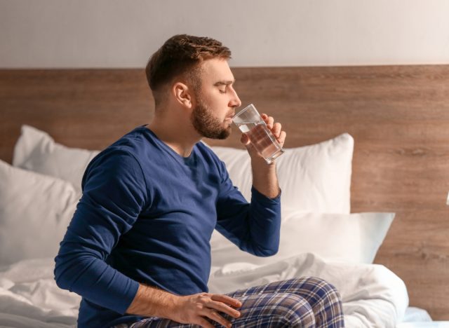 man drinking water in bed