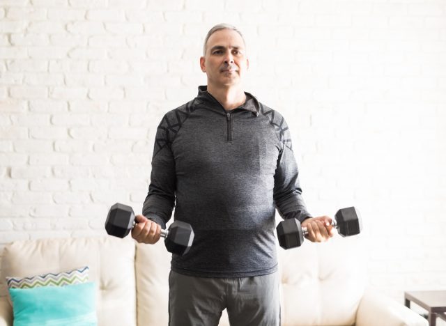 man working out with dumbbells at home in a bright room