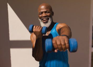 happy fit man in 50s holding dumbbells for HIIT workout to accelerate belly fat loss