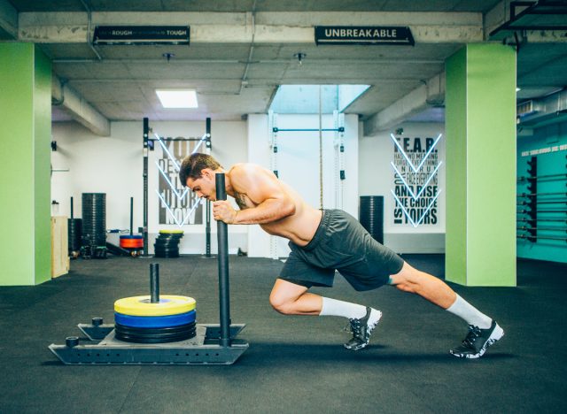 fit man doing sled push in gym to get rid of a pot belly