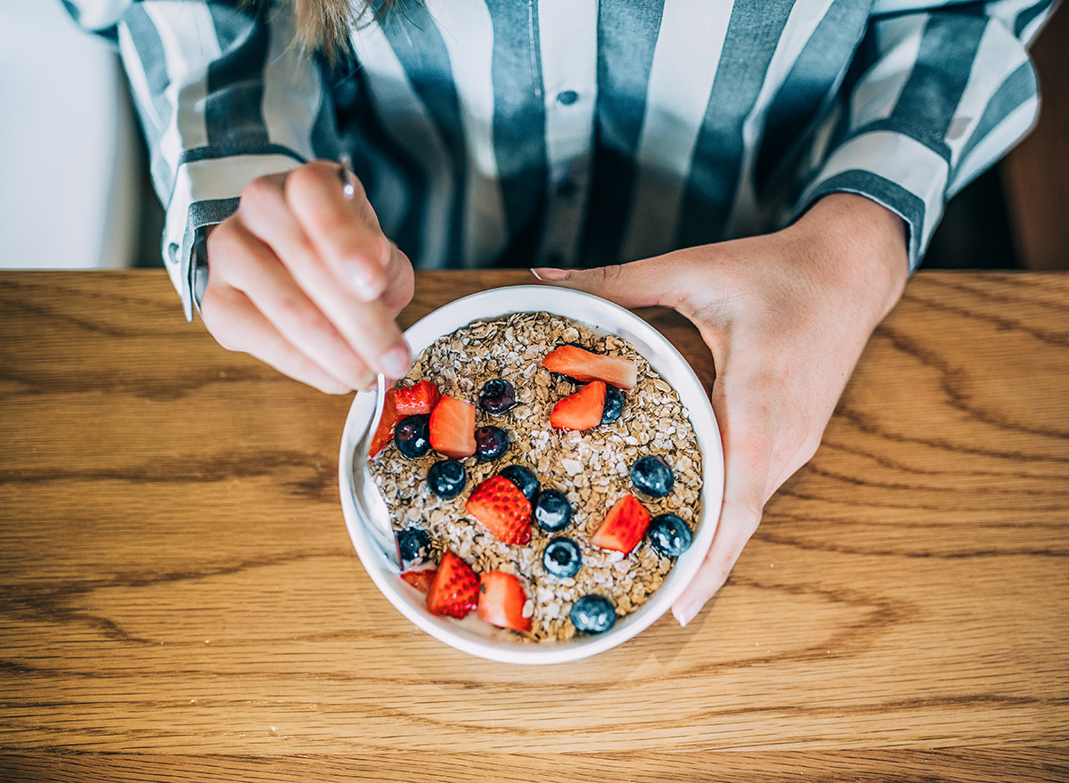 person eating oatmeal in the morning with berries