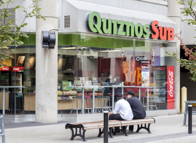 Men sitting outside of a quiznos