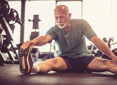 senior man stretching in gym