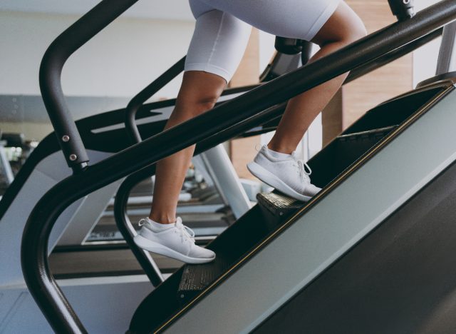 close up woman using stair climber at gym to melt belly fat fast
