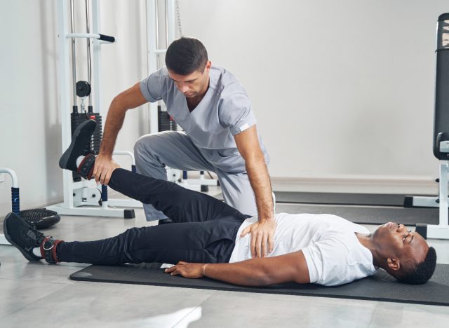 physical therapist helping patient do straight leg raise to strengthen weak knees