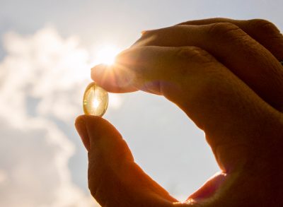 closeup hand holding vitamin D in front of sunshine