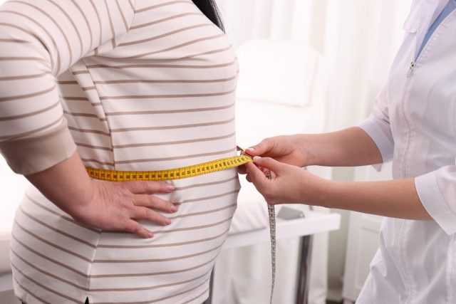 weight gain in middle age, doctor measuring patient's stomach