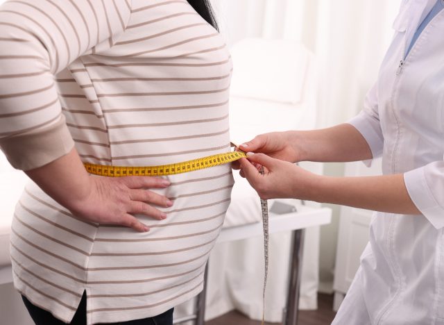 weight gain in middle age, doctor measuring patient's stomach