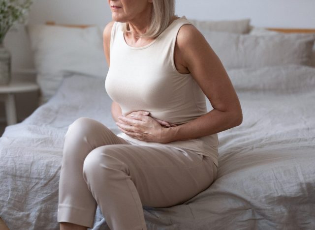 mature woman dealing with bad gut health, stomach pain on bed