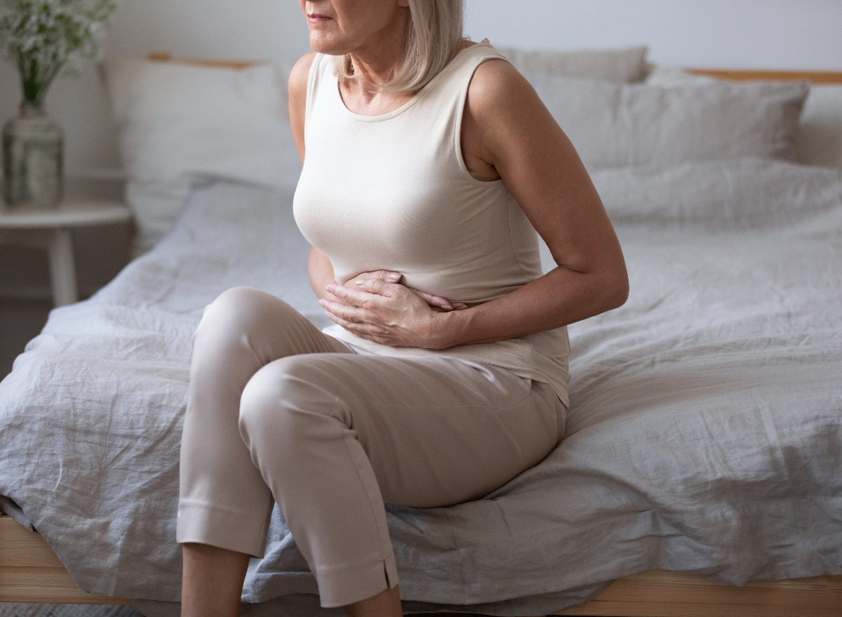 mature woman dealing with bad gut health, stomach pain on bed