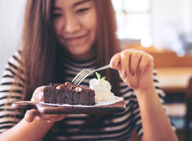 mujer comiendo pastel de brownie con crema batida