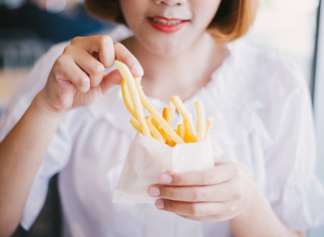 A woman eating French fries