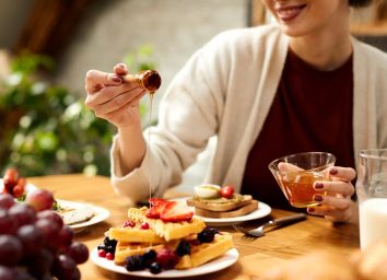 woman adding honey to a plate of healthy protein waffles