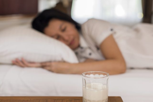 woman sleeping with glass of milk on nightstand