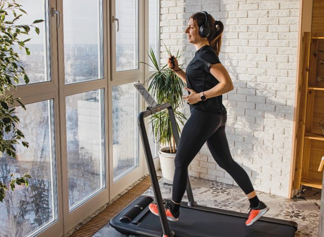 happy woman does home treadmill workout to burn fat