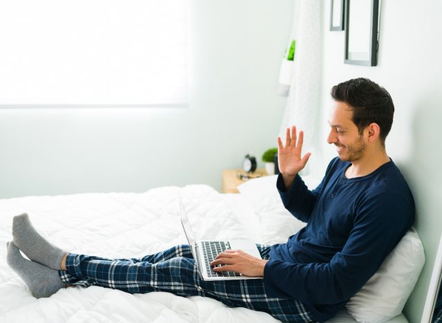 man working from home happy in PJs on laptop