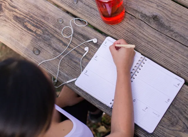 woman writing workout schedule in planner to jumpstart weight loss