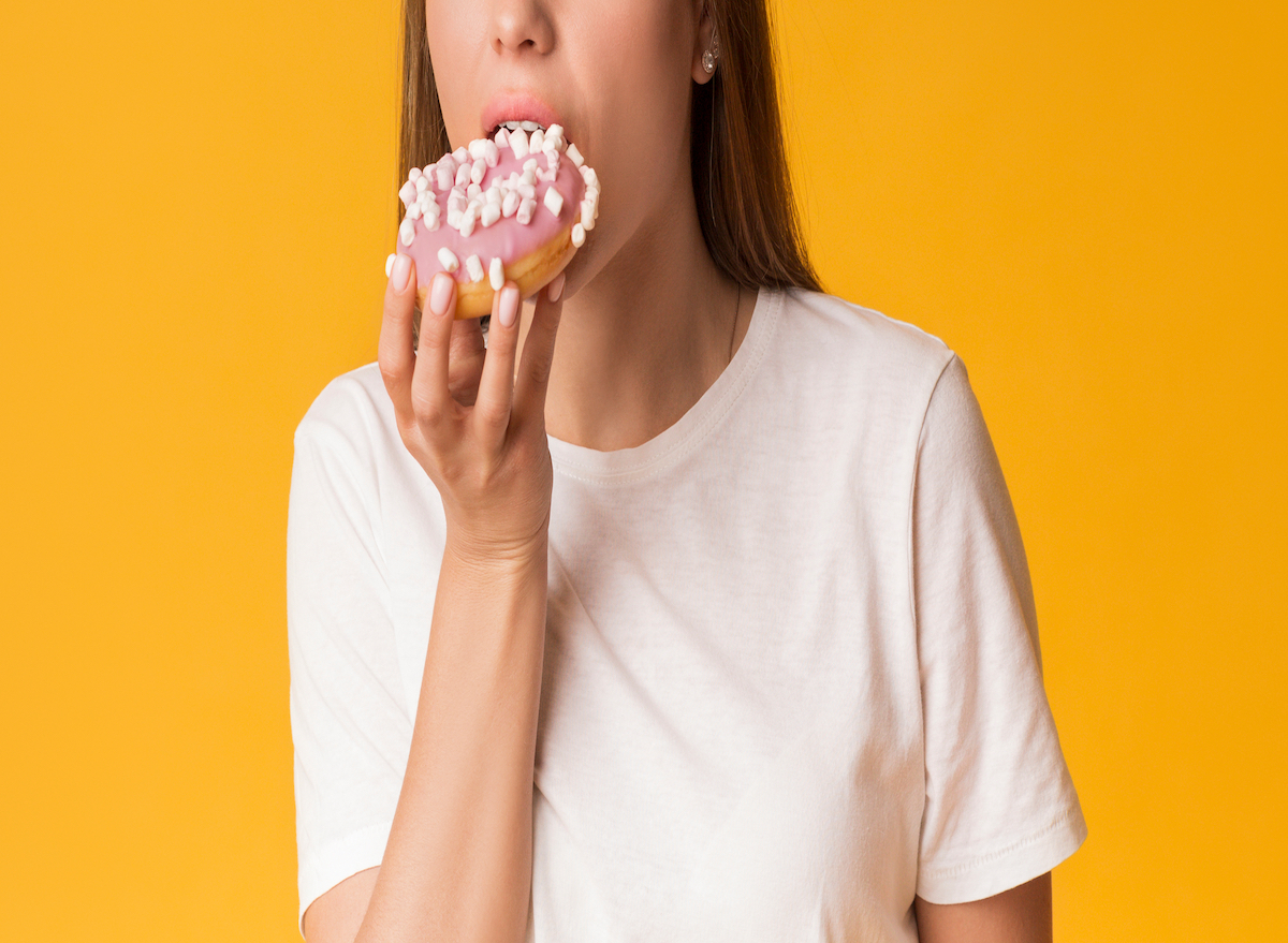 Cropped woman eating donut