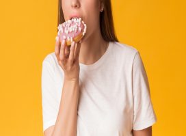 Cropped woman eating donut