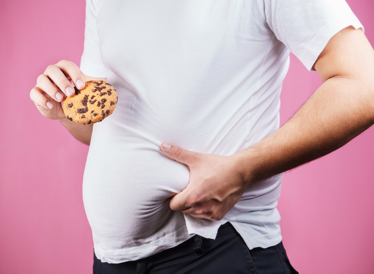 Man holding stomach with cookie