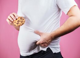 Man holding stomach with cookie