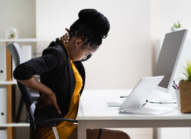 woman experiencing back pain from slouching at desk