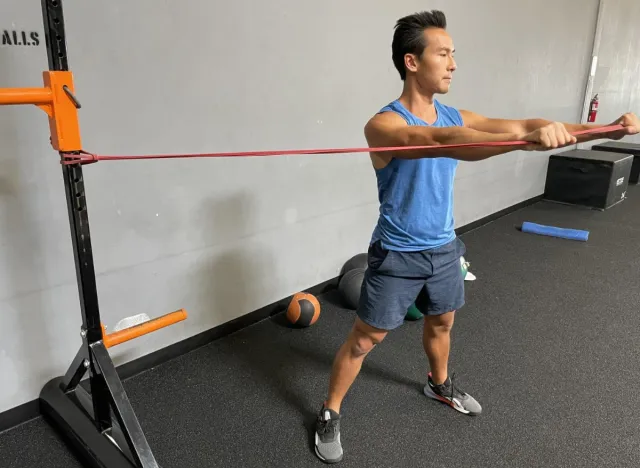 trainer doing band rotation chop to get rid of belly creases