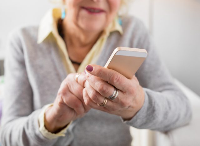 Iš arti vyresnio amžiaus moteris rašo žinutes, naudodama programą, kad patikrintų, ar nėra Alzheimerio ligos