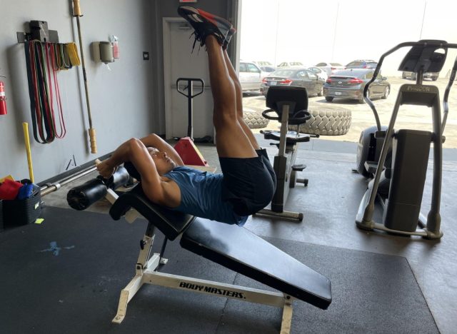 trainer performing decline bench leg raise to get rid of belly creases
