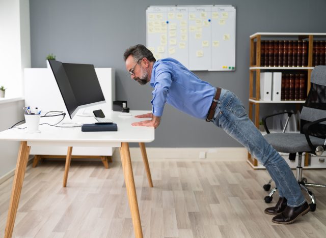 man doing desk pushups to burn calories while working
