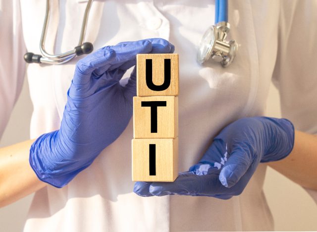 closeup doctor holding cubes that spell out UTI, medical concept, cause of UTIs