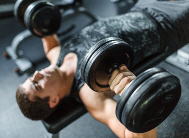 mature man working press with dumbbell, exercise to lose guts