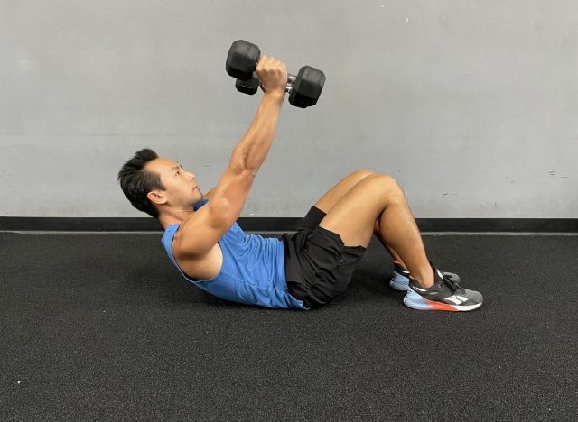 trainer performing dumbbell crunch to get rid of belly creases