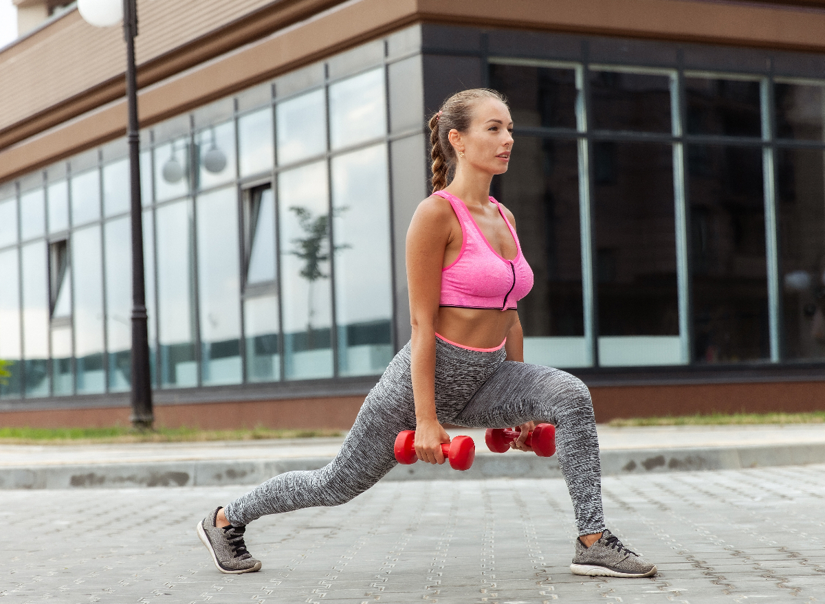 woman performing dumbbell lunges outside to speed up fat loss