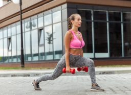 woman performing dumbbell lunges outside to speed up fat loss
