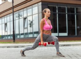 woman performing dumbbell lunges outside to speed up fat loss