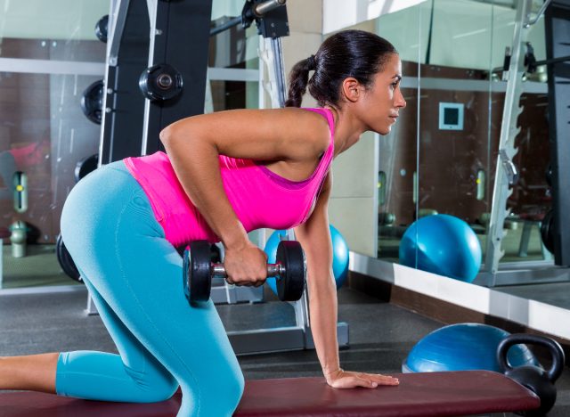 woman doing dumbbell row to break the plateau and lose weight