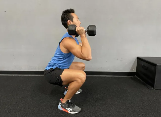 trainer doing dumbbell thrusters, demonstrating exercises to get rid of a pot belly