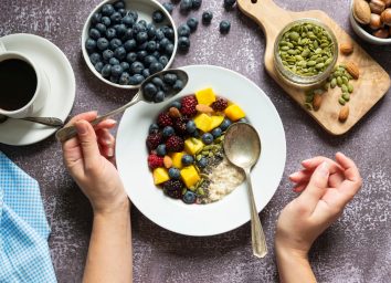 eating oatmeal with fruit, nuts, and seeds and coffee