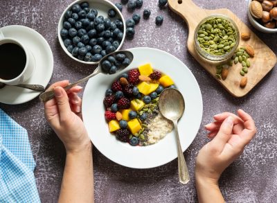 eating oatmeal with fruit, nuts, and seeds and coffee