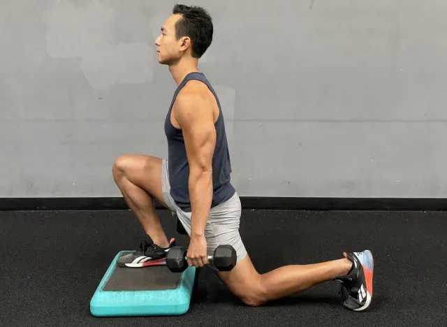 trainer demonstrating foot elevated split squat as part of workout to regain muscle mass