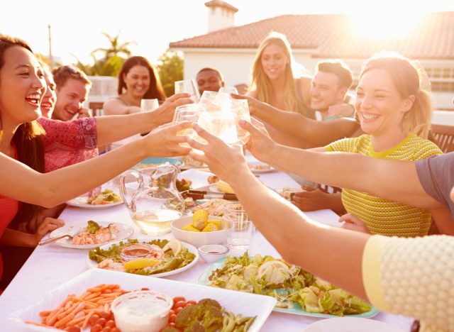 group of friends having a meal outside and clinking glasse