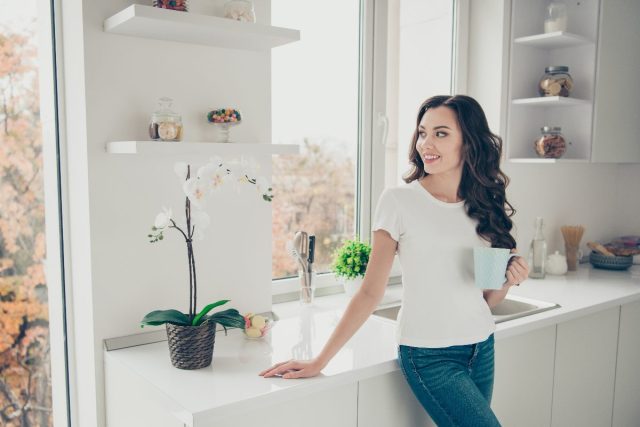 happy woman in clean home enjoys coffee in bright kitchen