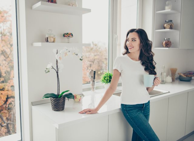 happy woman in clean home enjoys coffee in bright kitchen