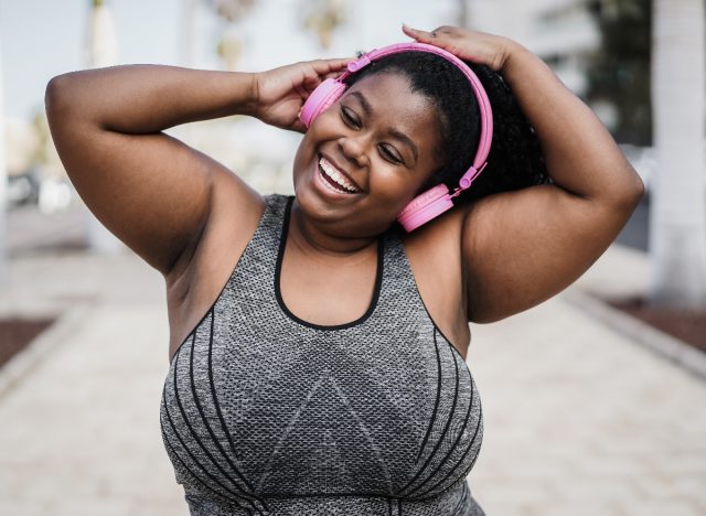 mujer feliz escuchando música afuera, baile cardio, entrenamiento rápido