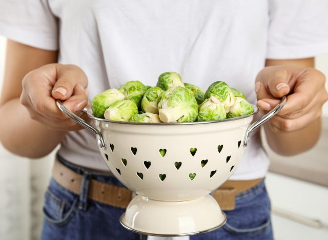 Holding a colander of brussels sprouts