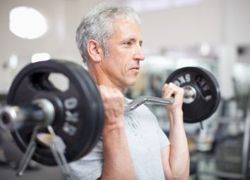 man in his 50s doing strength training to shrink belly fat