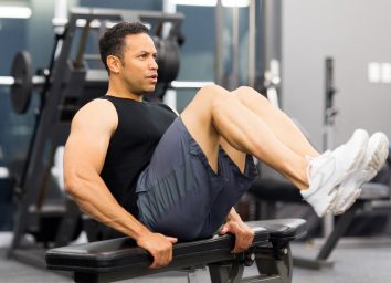 man in his 40s doing legs, core workout in gym