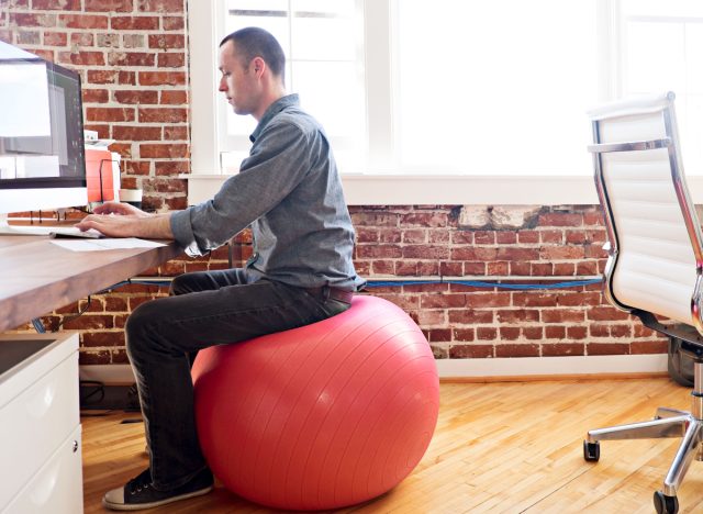 man using stability ball chair to burn calories while working
